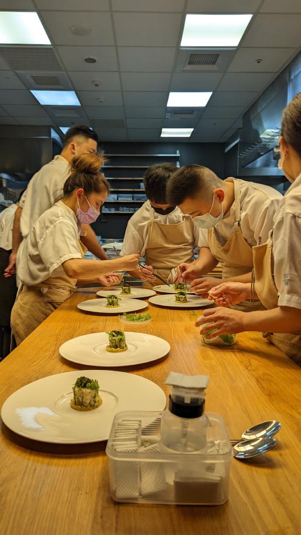 The kitchen staff plating on the monkfish dish